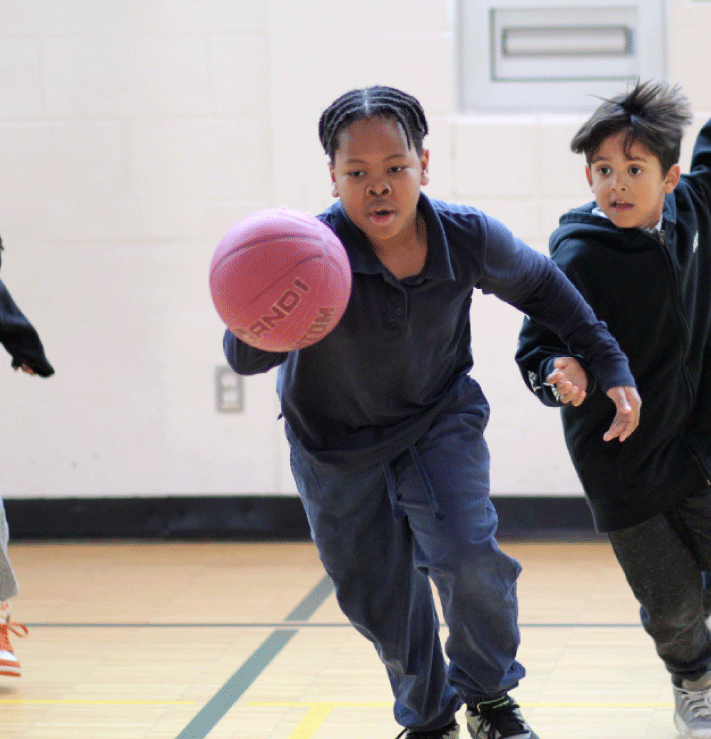A young African American male is attending after school program playing basketball.